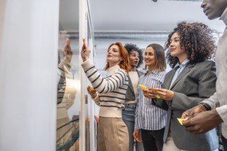 Side view of people participating in a creative process in a coworking using sticky notes on glass