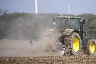 A tractor works a field, due to long dryness in spring, no rain for more than 4 weeks, the fields