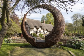 Anne Hathaway's Cottage framed by a round wicker seat, Shottery, Stratford-upon-Avon, Warwickshire,