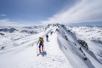 Two ski tourers on a mountain ridge, mountain landscape with snow, mountain panorama with peaks of