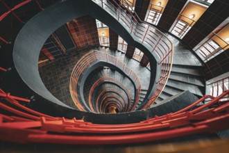 Dramatic spiral staircase with an open-height barrel and red railings, SPRINKENHOF, Hamburg,