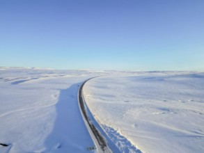 Beautiful aerial drone view landscape. Frozen road in winter in Iceland. Snowy roadsides during
