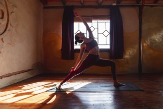 Young slim woman doing yoga on a mat, warrior pose. Posture of strength and balance. Concept of