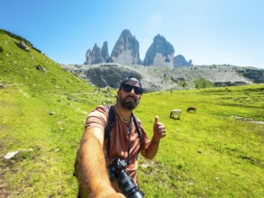 Photographer taking a selfie with thumbs up sign while hiking on a trail in tre cime di lavaredo,