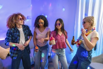 Four friends are singing karaoke and dancing together at a house party, enjoying music, drinks, and