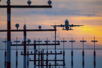 Runway lighting, approach aids, at Düsseldorf International Airport, sunset, aircraft taking off