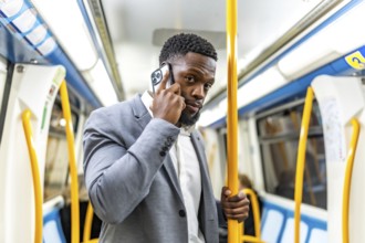 Young businessman commuting on public transport, using smartphone to stay connected while