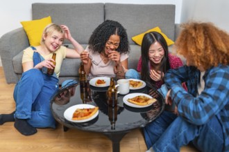 Four female friends sharing a meal of pizza and beer, laughing and having fun together in their