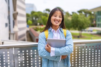 Cute chinese university student smiling at camera standing outdoors in the campus