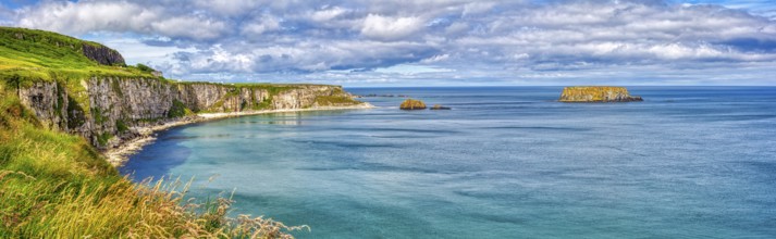Long coastline with steep cliffs and calm blue sea under cloudy skies, County Antrim Coast