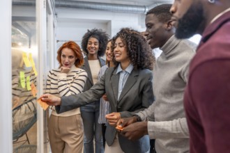 Hispanic woman sticking an adhesive note to a board during brainstorming in a coworking space