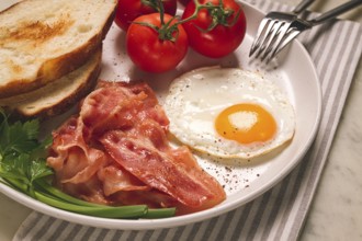 Frühstück, Spiegelei, Speck und Brot, mit Kirsche, auf einem hellen Hintergrund, hausgemacht, keine