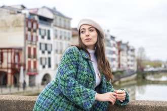 Cute woman in beret standing next to the river while visiting the city