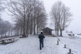 A young man walking next to the refuge of mount aizkorri in gipuzkoa. Snowy landscape by winter