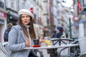 Woman with beret looking away and drinking coffee in a sidewalk cafeteria