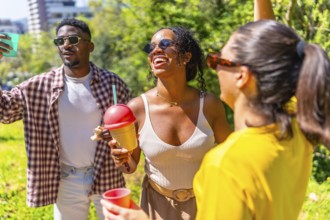 Cheerful group of friends laughing, dancing, and enjoying refreshing drinks in a vibrant park