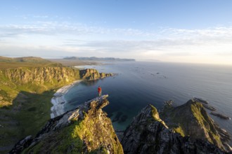 Evening mood, mountaineer standing on a rocky outcrop on the summit of Måtind, view of coastal