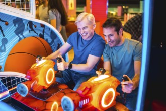Two male friends enjoying their free time playing arcade basketball simulator together, laughing