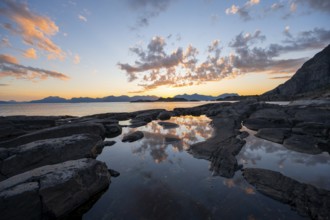 Clouds reflected in a small pond on a rocky coast, coastal landscape at sunset, Henningsvær,