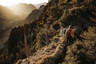 Hiker in the Allgäu at sunset in spring on the Zirmgrat near Pronten in the Allgäu