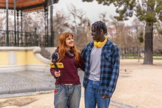 Two young content creators walking and talking in a park, recording audio with a mobile phone and