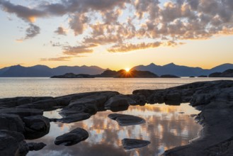 Clouds reflected in a small pond on a rocky coast, coastal landscape at sunset, Henningsvær,