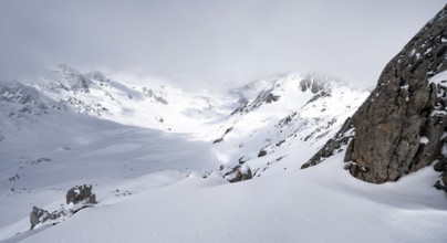View of cloudy valley from the summit of Piz Laviner, mountain landscape in winter, Grisons Haute