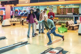 Diverse group of young adults having fun bowling together, enjoying a weekend leisure activity