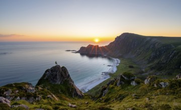 Climber on rocks in front of picturesque landscape, view of coastal landscape at sunset, cliffs and