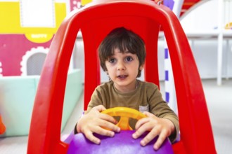 Preschooler having fun driving an imaginary car in kindergarten, engaging in playful learning and