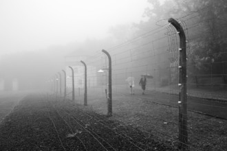 Reconstructed camp fence with people in the fog at beech forest concentration camp, now a