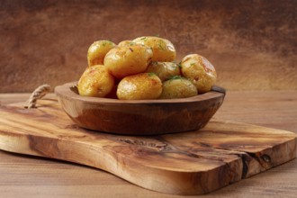 Baked new potatoes, with butter and dill, on a wooden plate, homely, rustic, no people