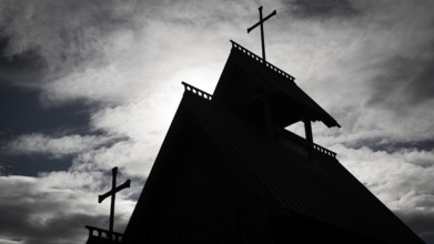 The silhouette of a church with several crosses against a cloudy sky, backdrop Kristin
