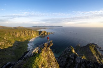Evening mood, mountaineer standing on a rocky outcrop on the summit of Måtind, view of coastal