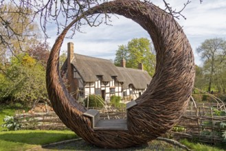 Anne Hathaway's Cottage framed by a round wicker seat, Shottery, Stratford-upon-Avon, Warwickshire,