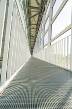 Symmetrical corridor with metal floor and large glass windows, Motorworld Böblingen, Germany,