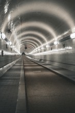 Long, illuminated tiled tunnel with symmetrical curves, old Elbe tunnel, Hamburg, Germany, Europe