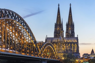 Cologne Cathedral, illuminated in the evening. Hohenzollern Bridge, railway bridge over the Rhine.