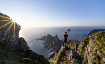 Mountaineer on the summit of Måtind or Måtinden, view of picturesque coastal landscape with sun