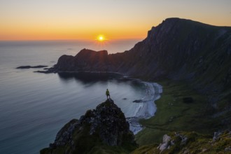 Climber on rocks in front of picturesque landscape, view of coastal landscape at sunset, cliffs and