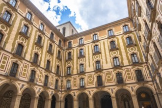 Low angle view of the courtyard of montserrat monastery, showing arched walls, balconies, and