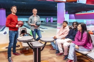 Multi ethnic group of friends enjoying a lively bowling game at the alley, sharing laughter and