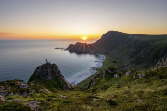 Climber on rocks in front of picturesque landscape, view of coastal landscape at sunset, cliffs and