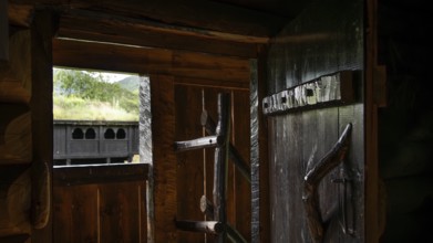 View from a small room in a wooden hut through an open wooden door to a traditional wooden