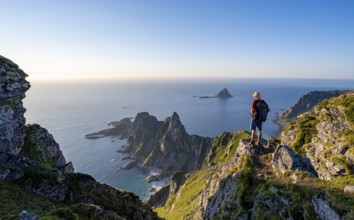 Mountaineer on the summit of Måtind or Måtinden, view of picturesque coastal landscape, rocky coast