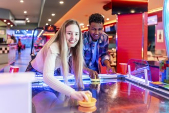 Two young friends enjoying a game of air hockey in a vibrant entertainment center, showcasing