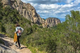Female tourist walking on a hiking trail in montserrat mountains near barcelona with the santa