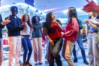 Young multiethnic friends are dancing and having fun together at a bowling alley, enjoying the