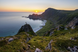 Climber on rocks in front of picturesque landscape, view of coastal landscape at sunset, cliffs and