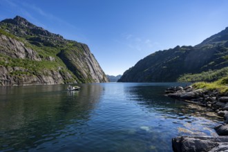 Motorboat with tourists in the fjord Trollfjord, mountains reflected in the water, fjord landscape